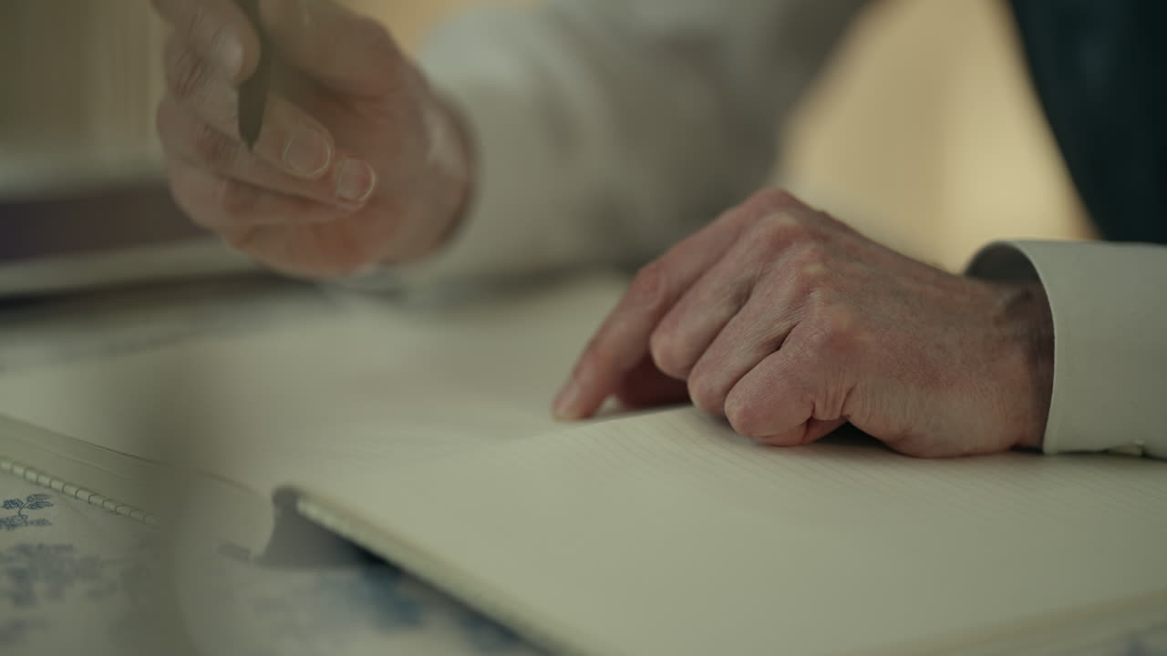 Detailní záběr rukou píšících a přemýšlejících do sešitu