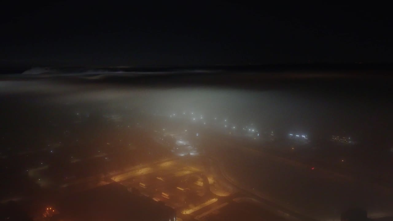 Nighttime above the foggy Saint-Constant village with streetlights casting a soft glow in winter, Quebec, Canada.
