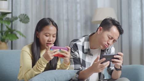 father and daughter playing games on smartphones