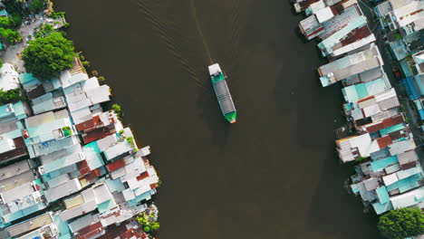 Vista-Aérea-De-Un-Barco-De-Pasajeros-Que-Navega-Con-Gracia-Por-El-Río-De-La-Ciudad,-Rodeado-De-Imponentes-Rascacielos-Y-Una-Vibrante-Vida-Urbana.