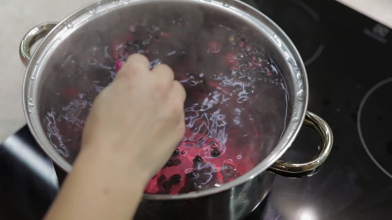 Stir the berries in pot with boiling water. Cooking compote. Kitchen