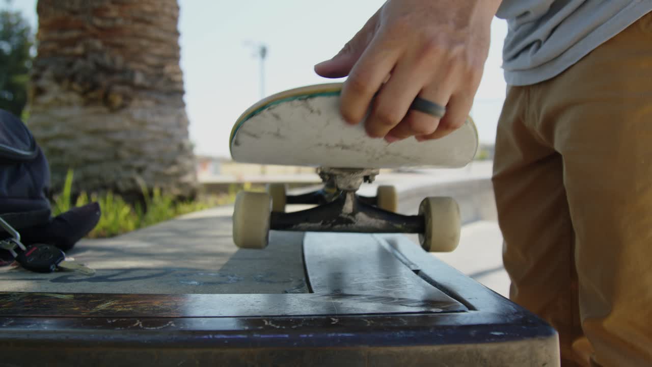 A skateboarder holds a skateboard on a concrete ledge and flips it with their hands