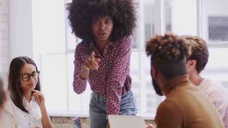 una mujer negra del milenio se presenta a sus colegas creativos en una sala de reuniones, disparada en la inclinación
