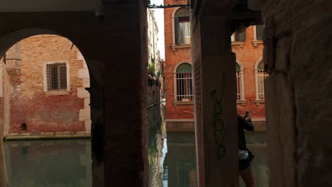 slow pov dolly walk in mysterious narrow alley with beautiful water canal at the end. holiday trip in venice,italy
