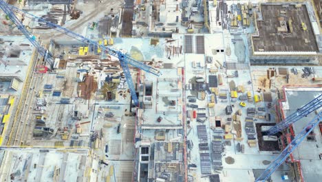 aerial bird eye view of a construction site building cranes looking down industrial machinery area around residential urban apartments