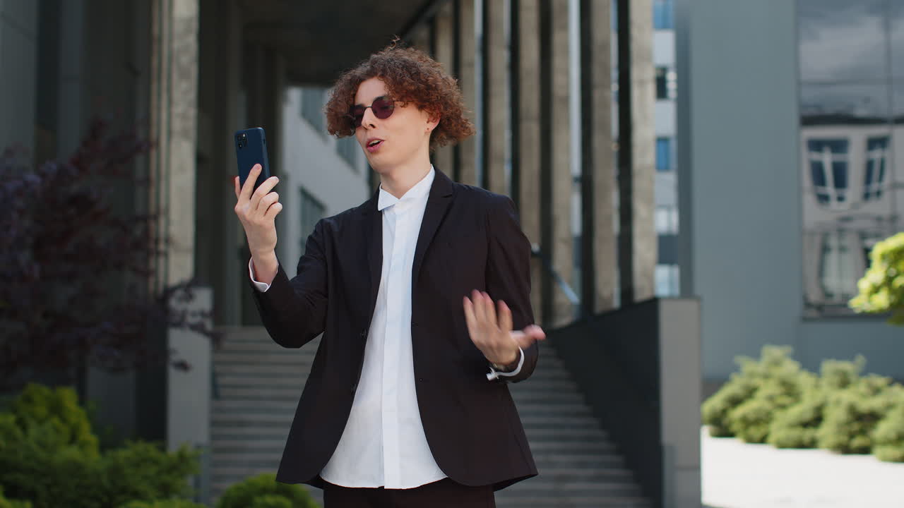 비즈니스맨이 전화를 하고 있습니다. 온라인 대화입니다. 스피커에서 대화하고 있습니다. 사무실 밖에서 인사합니다.