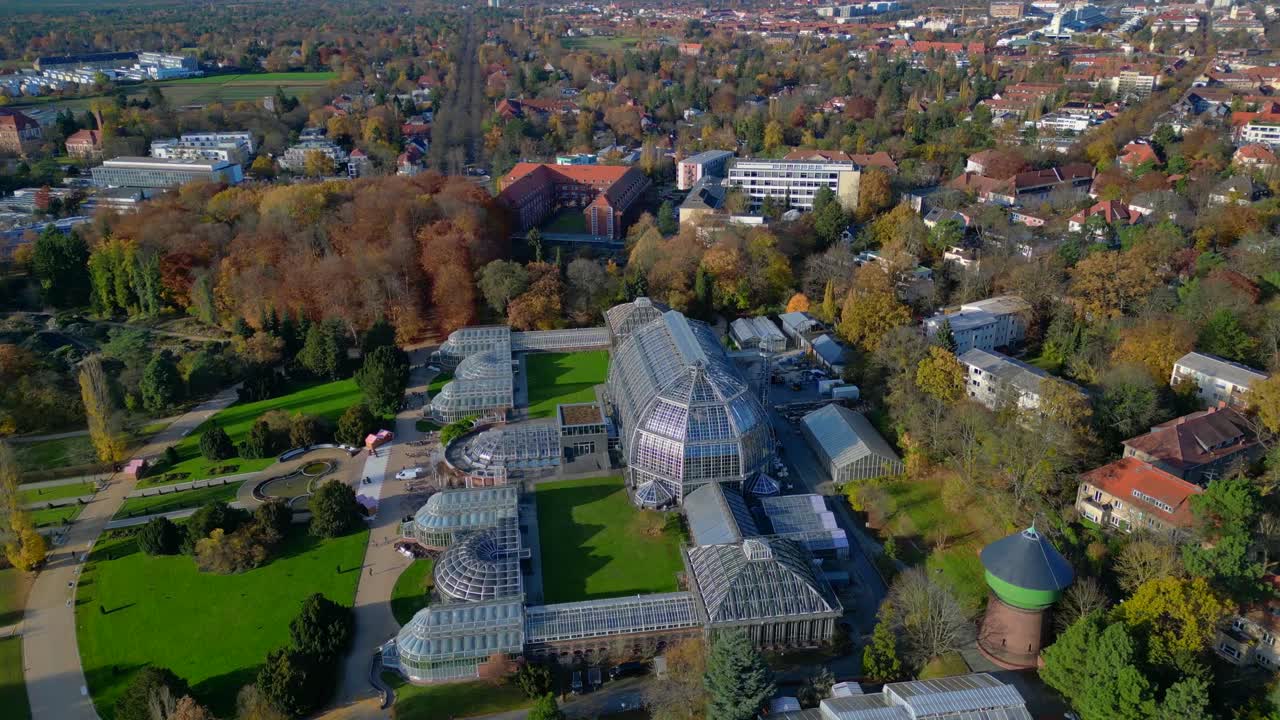 Berlin botanical garden Dome construction glasshouses surrounded by autumn trees and city landscape. Marvelous aerial view flight wide orbit overview drone