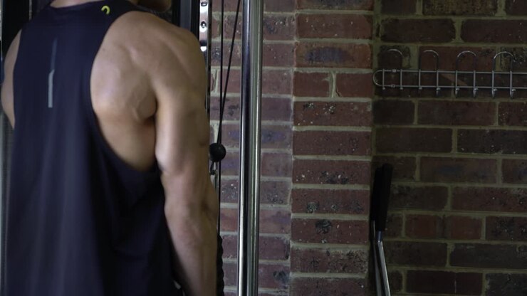 Tattoo man muscles in home gym doing tricep cable pulldown blurry