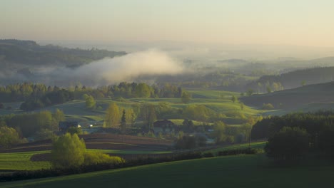 fog dancing over a green valley with fertile fields