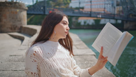 smiling lady enjoying literature at river landscape closeup. girl reading book