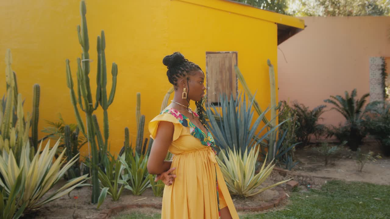 Donna elegante in abito giallo in un giardino tropicale