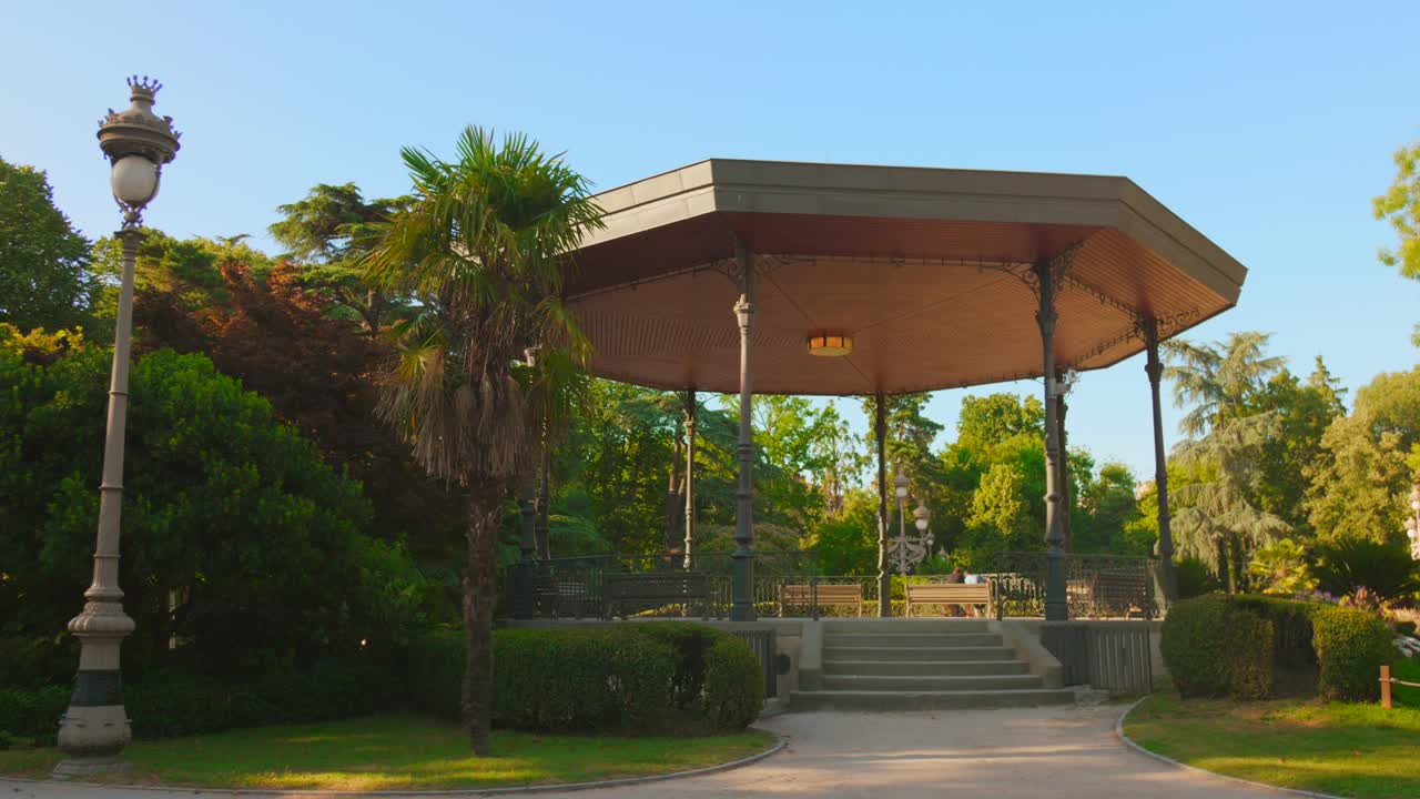 Hexagonal gazebo with metal pillars in the middle of the Grand Rond park, surrounded by palm trees and trimmed bushes