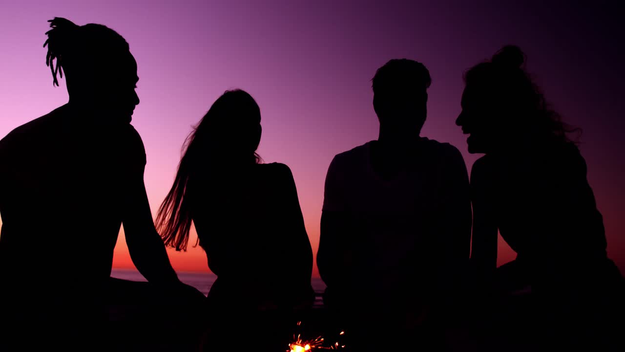 Young adult friends talking on the beach at sunset 4k
