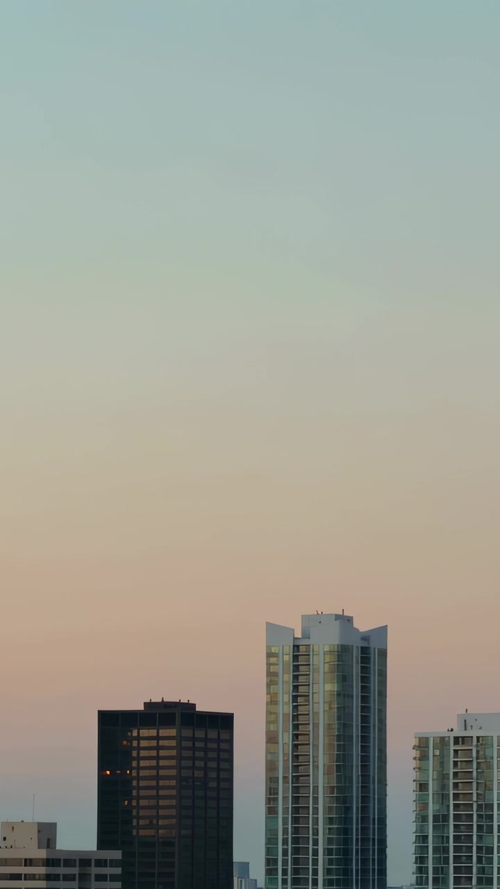 Video vertical: Cámara inclinándose, revelando tres torres en la azotea, mostrando un degradado de cielo en tonos pastel.