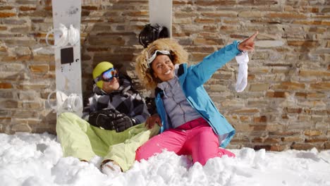 laughing woman sitting next to friend in snow