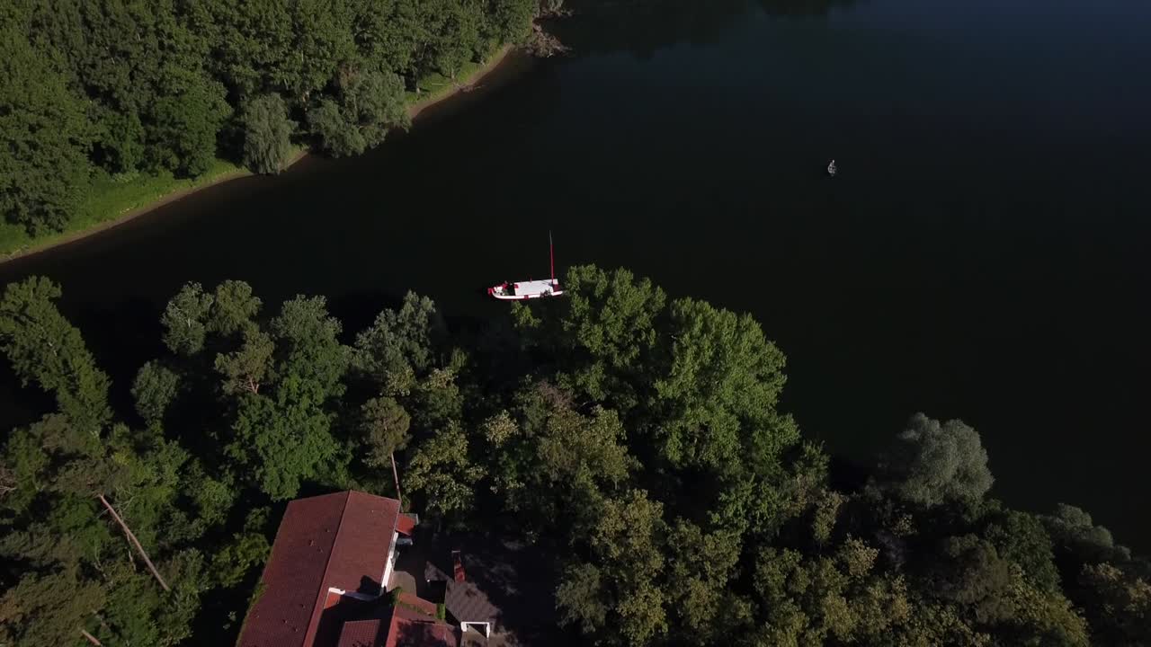 Drone staying at high altitude in a fixed position over an island in a lake while camere movement moves up to the horizon in Germany
