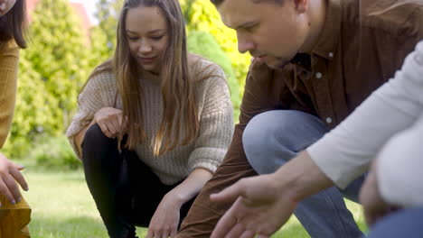 close-up view of a group of men and women friends squatting and calculating distance between petanque balls in the park