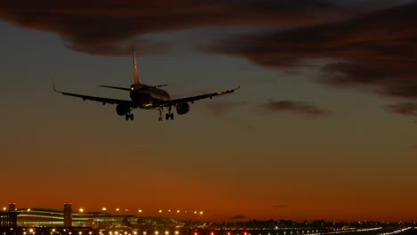 Toma-De-Seguimiento-Del-Aterrizaje-De-Un-Avión-Comercial-En-El-Aeropuerto-De-Barcelona-Al-Atardecer