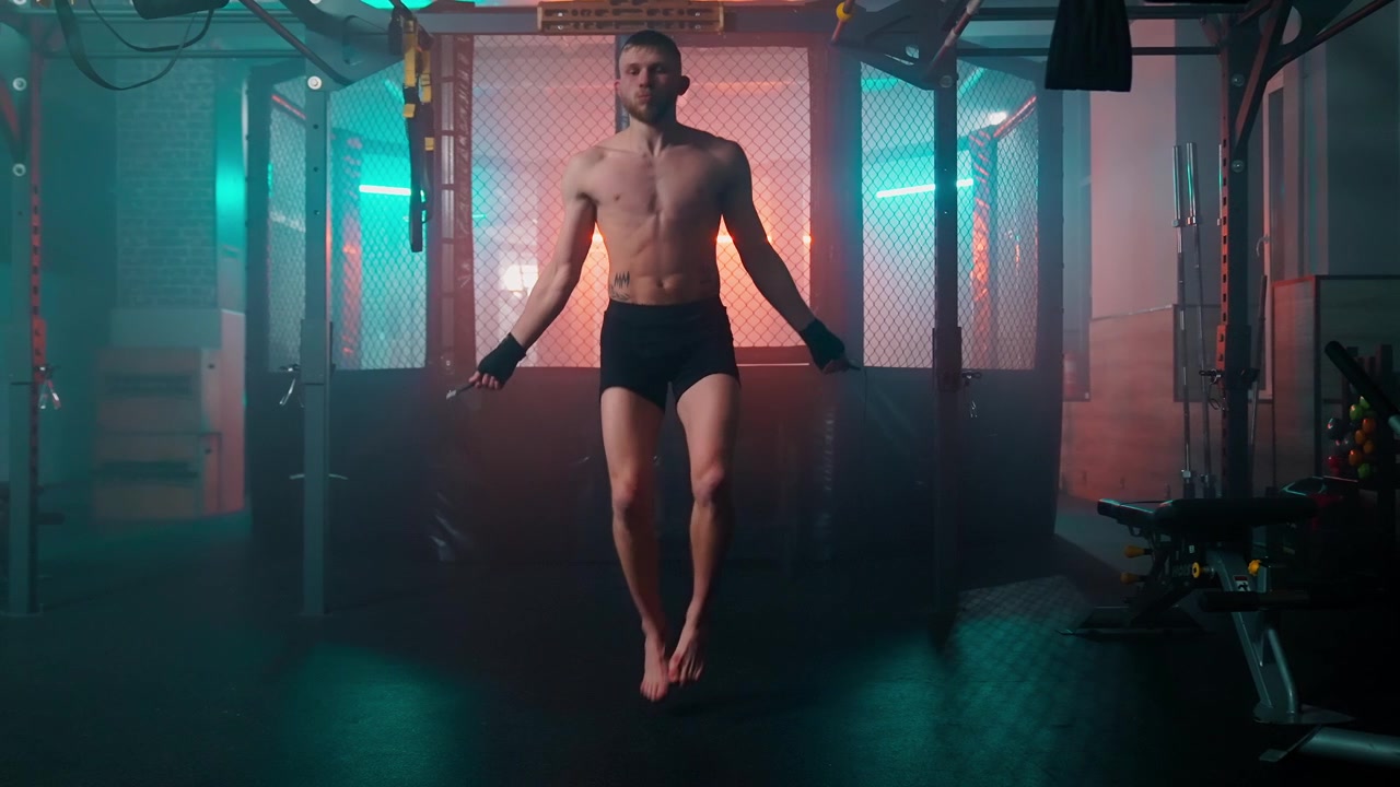 Uomo muscoloso che salta la corda durante un allenamento intenso in una palestra moderna
