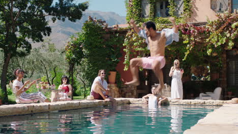 Hombre-Divertido-Saltando-En-La-Piscina-Salpicando-A-Amigos-De-Vacaciones-En-Una-Hermosa-Villa-Gente-Relajándose-En-Un-Cálido-Día-De-Verano-Turistas-Disfrutando-De-Vacaciones-Mediterráneas-4k