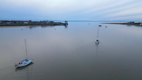 flying in between yachts on calm water at dusk on the river wyre estuary fleetwood lancashire uk