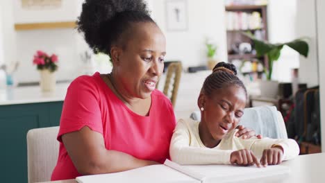 Video-Einer-Lächelnden-Afroamerikanischen-Großmutter,-Die-Ihrer-Enkelin-Beim-Lesen-Der-Blindenschrift-Zuhört