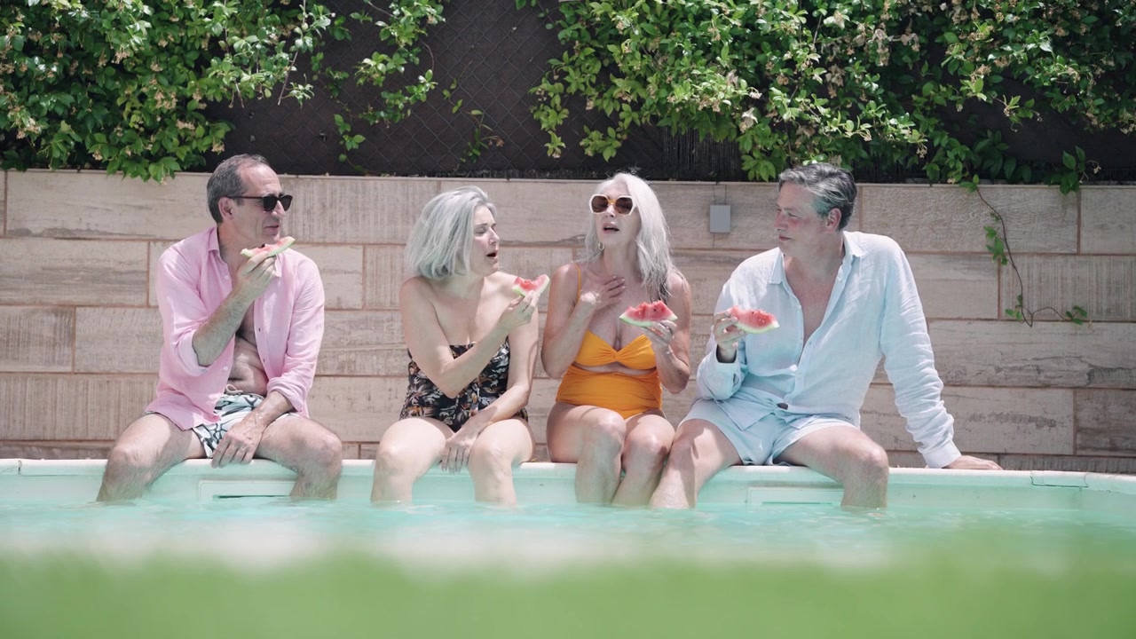 Group of Mature Friends Eating Watermelon by the Swimming Pool