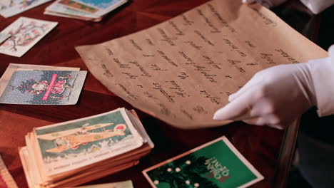 santa's hands in white gloves holding the letter. grandpa claus puts the letter on the table among christmas cards.