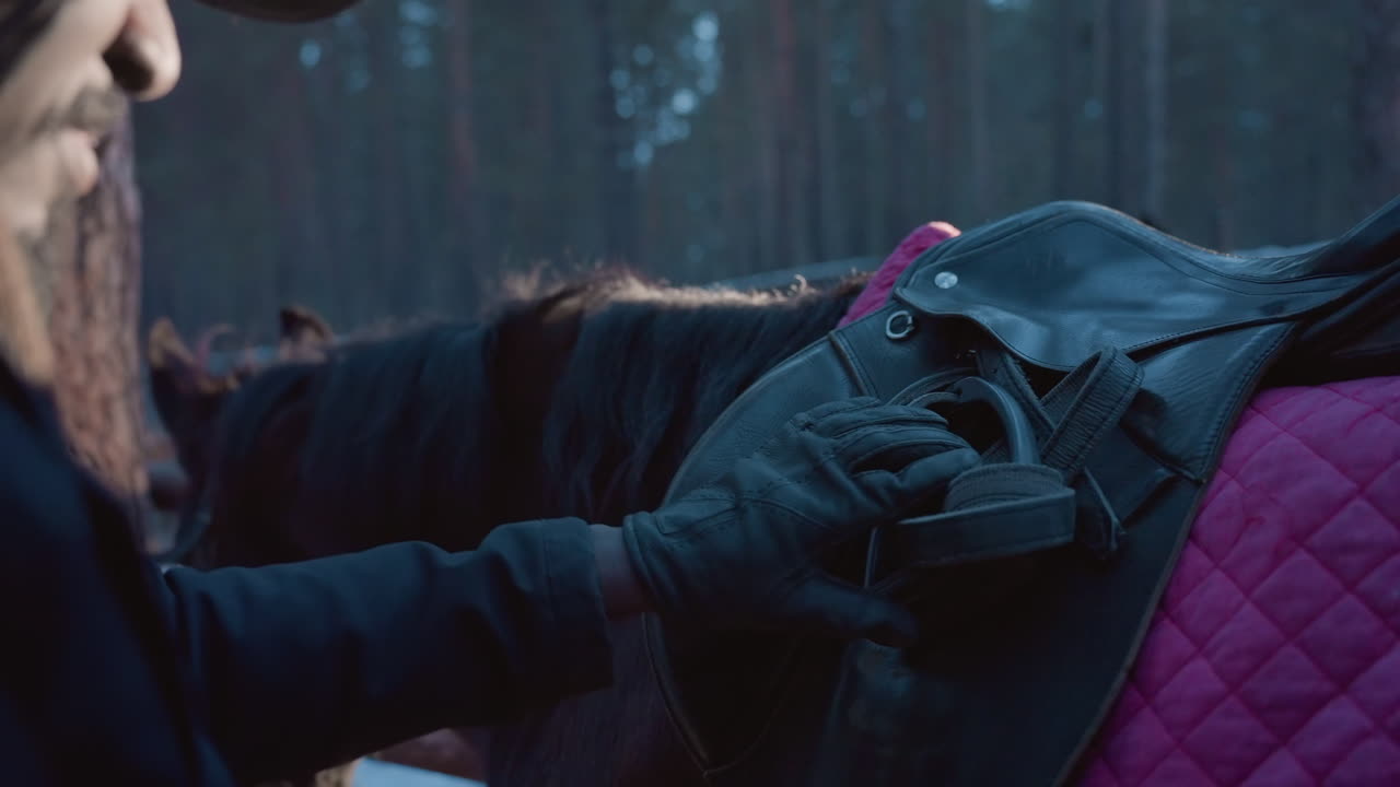 Спокойная подготовка к верховой езде: сосредоточенный всадник дорабатывает снаряжение в лучах яркого солнца, безмятежный момент регулировки седла при естественном освещении перед началом верховой езды.