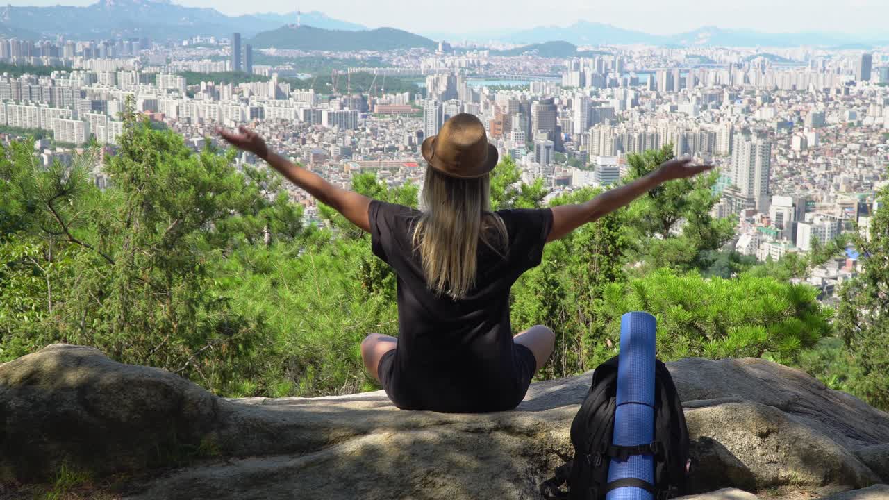 chica practicando la postura del loto de yoga y meditando en el borde de una montaña con vistas al horizonte desde la montaña gwanaksan en corea del sur