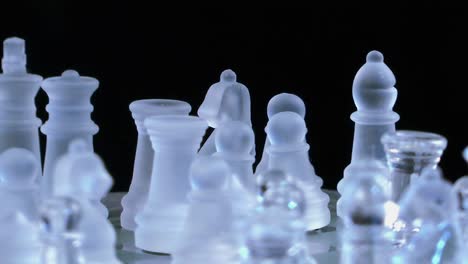 Glass-chess-pieces-on-a-board,-shiny-and-transparent-figures-on-chessboard-in-rotation-mode,-chess-playing-concept