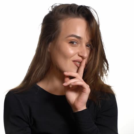 a gorgeous girl in a black jumper is throwing back her hair and smiling on a white background in the studio. close-up