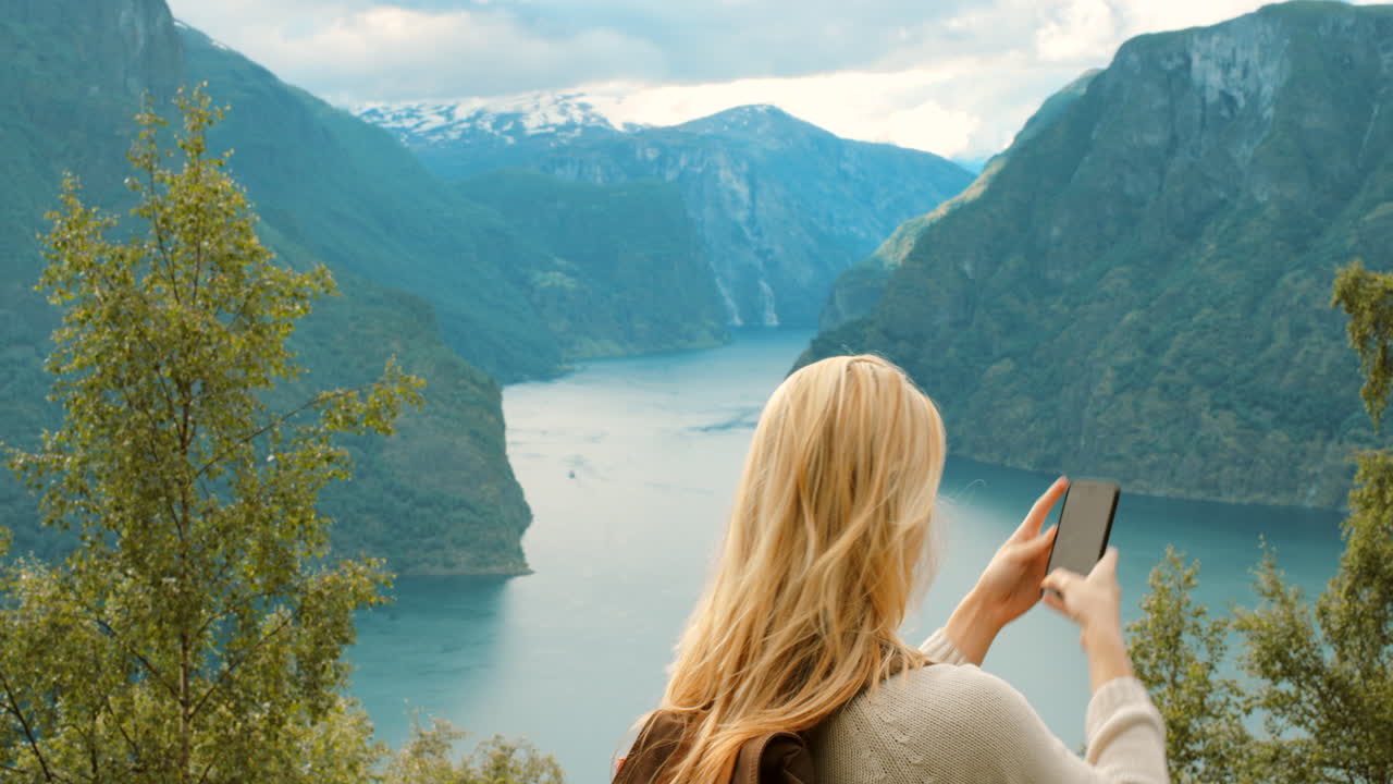 una mujer tomando una selfie en un fiordo noruego.