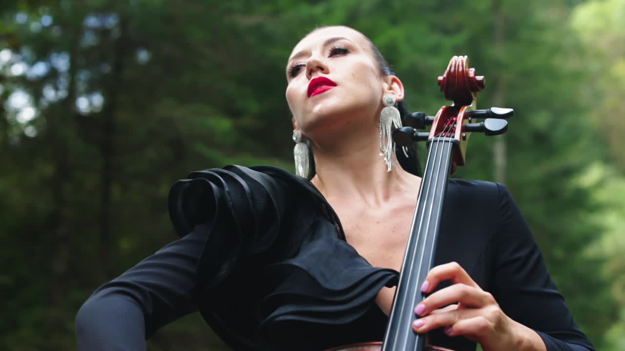 Girl playing cello outdoor. Beautiful young woman playing cello outdoors