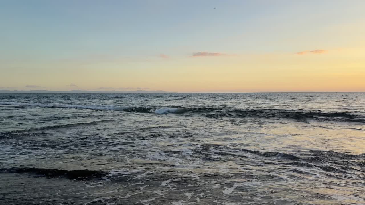Onde dell'oceano che si infrangono sulla spiaggia al tramonto