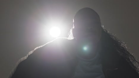 close up backlit head and shoulders studio portrait shot of young woman street dancing in spotlight