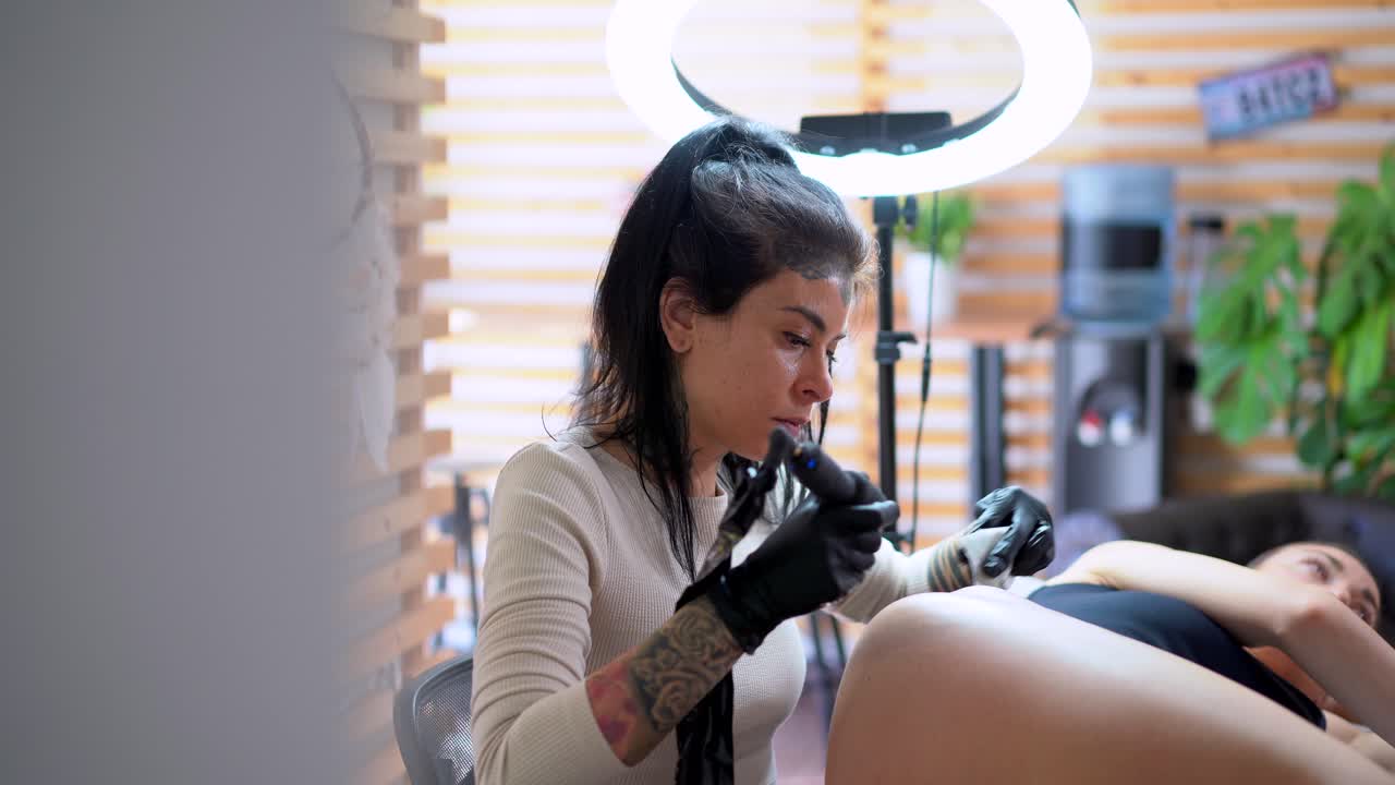 tatuador dibujando tatuaje en la cadera del cliente en el estudio