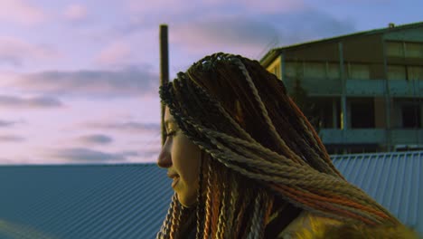 mujer con trenzas en un techo al atardecer