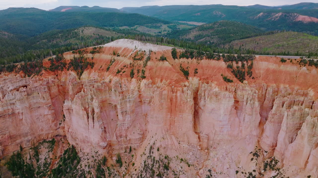Stunning huge rock of coral color in Bryce National Park. Mountains overgrown with pine forest at backdrop. Aerial view.