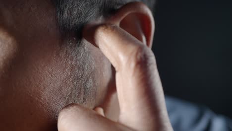 close-up of a man's ear and finger