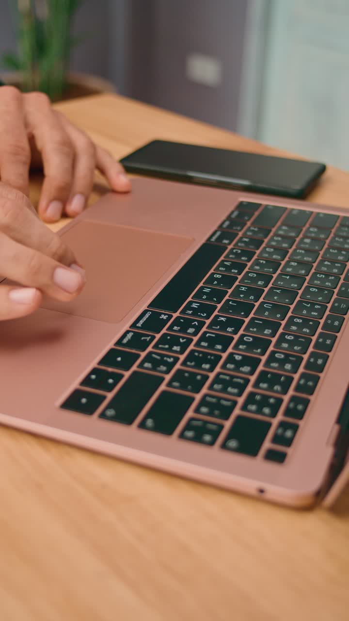 Person using laptop and smartphone on wooden desk