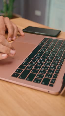 person using laptop and smartphone on wooden desk
