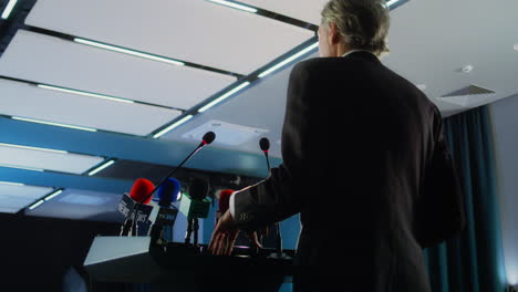 female politician makes an announcement, answers journalists questions and gives interview for media. confident representative of the european union during press conference. backdrop with eu flags.