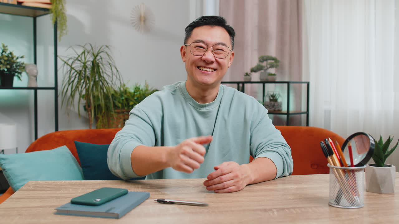 Happy asian middleaged man looking approvingly at camera show thumb up like positive sign good news