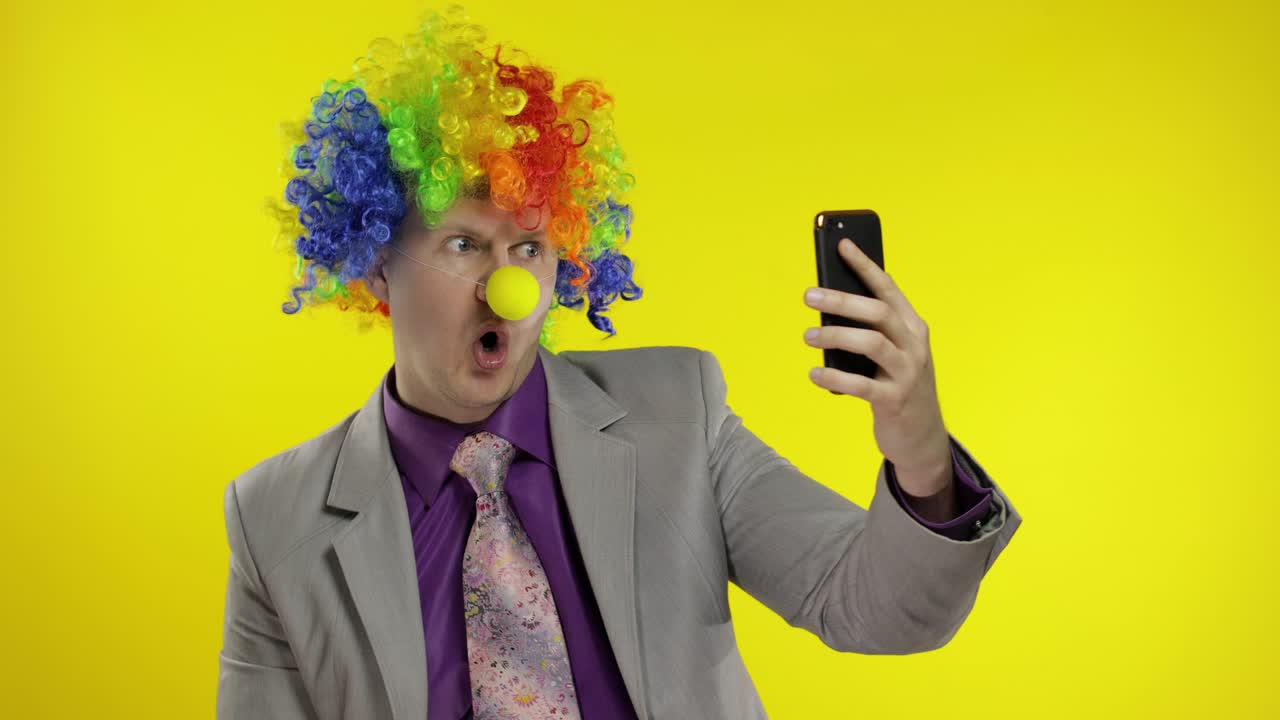 payaso hombre de negocios empresario jefe en peluca haciendo selfies usando teléfono inteligente