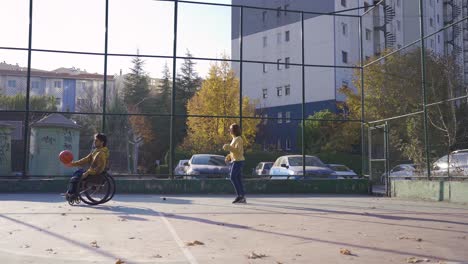 Behinderter-Spielt-Draußen-In-Seinem-Rollstuhl-Mit-Seiner-Freundin-Basketball.