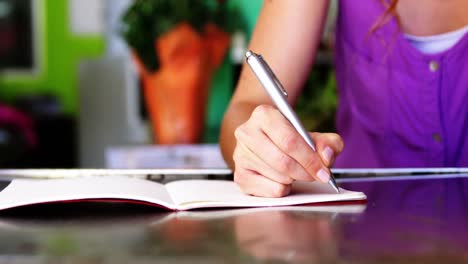 Florista-Femenina-Escribiendo-En-Un-Libro