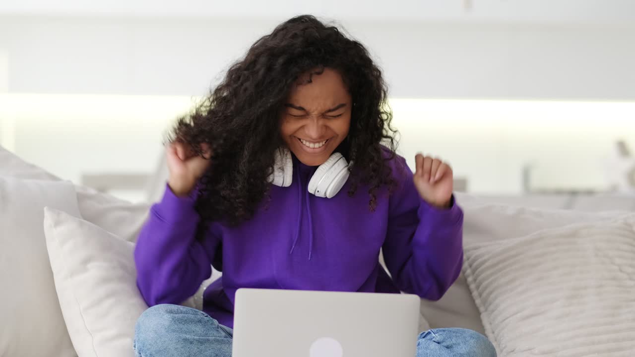 feliz chica afroamericana atractiva celebrando la victoria levantó los brazos trabajando en la oficina trabajando remotamente desde casa mujer negra usando computadora portátil aprendizaje a distancia educación en línea y trabajo