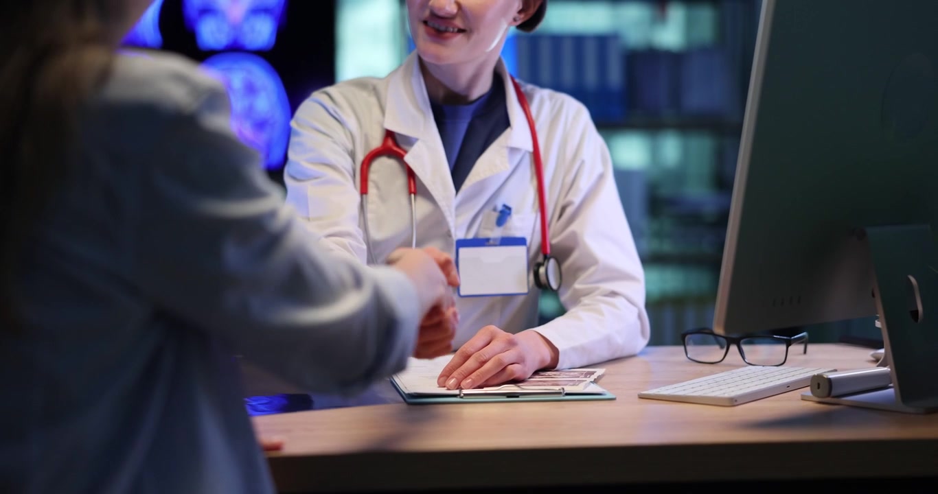 Medico con stetoscopio visita una donna seduta alla scrivania.