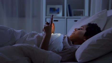 Frau-Mit-Smartphone-Im-Bett-Zu-Hause-In-Der-Nacht.Technologie,-Internet,-Kommunikation-Und-Menschen-Konzept-Junge-Afroamerikanische-Frau-Mit-Smartphone-Im-Bett-Zu-Hause-In-Der-Nacht-Liegen